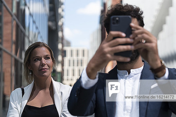 Businessman with smartphone and businesswoman in business district in the city