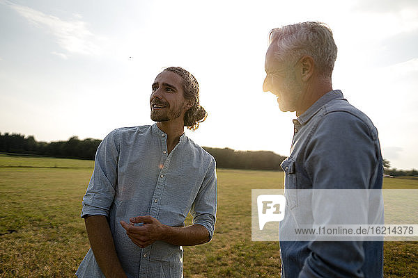 Happy father with adult son on a meadow in the countryside at sunset