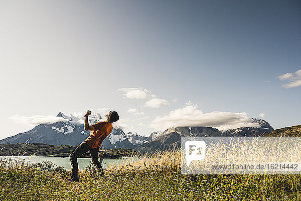 Man showing winning gesture while standing near Lake Pehoe in Torres Del Paine National Park  Chile Patagonia  South America