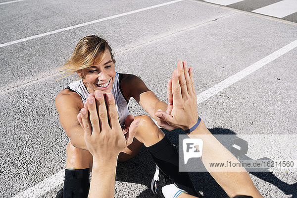 Lächelnde Frau  die ihrem Freund beim Sport auf der Straße in der Stadt die Daumen drückt