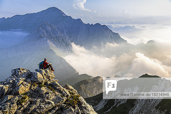 Man sitting and admiring mountain landscape during sunrise at Bergamasque Alps  Italy