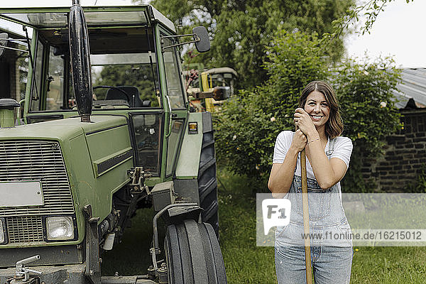 Porträt einer selbstbewussten jungen Frau  die an einem Traktor auf dem Lande steht