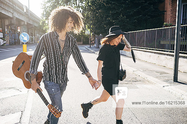 Glückliches Paar  das an einem sonnigen Tag auf einer Straße in der Stadt spazieren geht