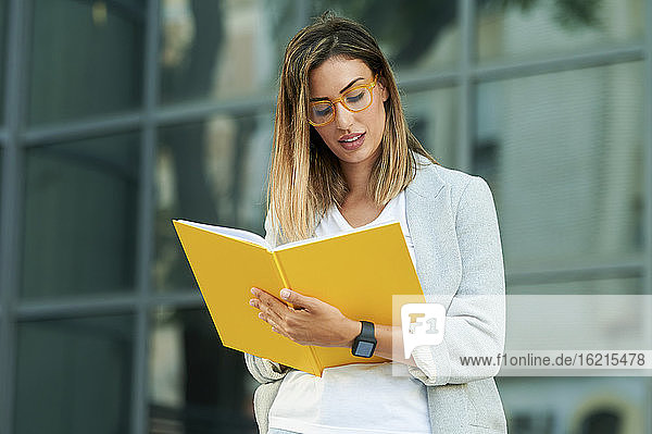 Businesswoman writing in notebook against office building