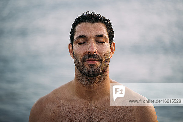 Nahaufnahme eines attraktiven Mannes ohne Hemd mit geschlossenen Augen am Meer