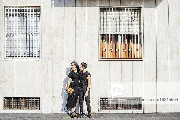 Lächelndes lesbisches Paar vor einem Gebäude in der Stadt