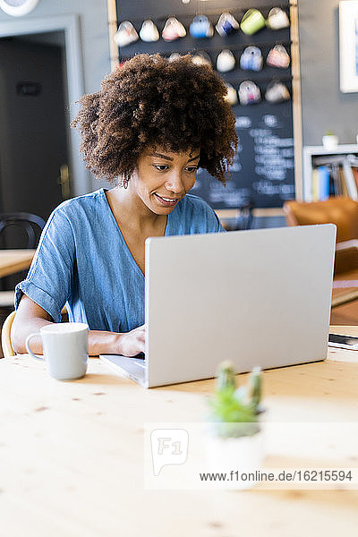 Junge Frau benutzt Laptop in einem Kaffeehaus