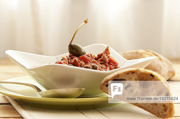 Schale mit Tomatensauce  Kapern und Brot auf Holztisch  Nahaufnahme