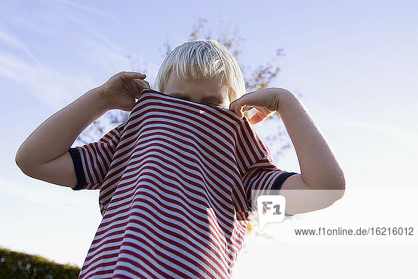Kleiner Junge (4-5) trägt ein gestreiftes Hemd  flacher Blickwinkel