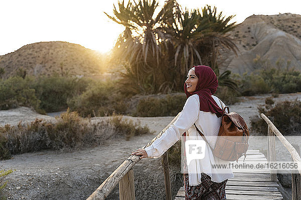 Lächelnde junge Touristin im Hidschab auf einer Holzbrücke