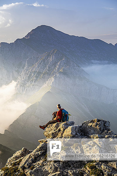 Man sitting on top of mountain peak at Bergamasque Alps  Italy