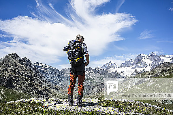 Mann bewundert die Aussicht  während er auf einem Berggipfel in den westlichen Rätischen Alpen steht  Sondrio  Italien