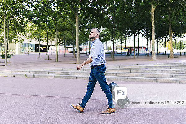Businessman walking with suitcase in office park