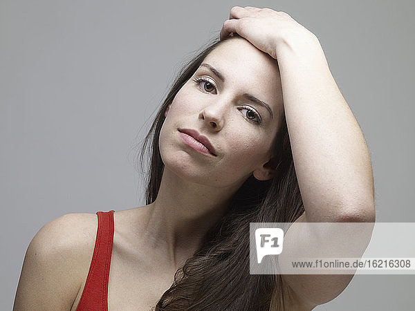 Portrait of young woman against grey background  close up