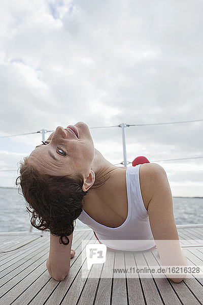 Germany  Baltic Sea  Lübecker Bucht  Young woman sitting on yacht  rear view