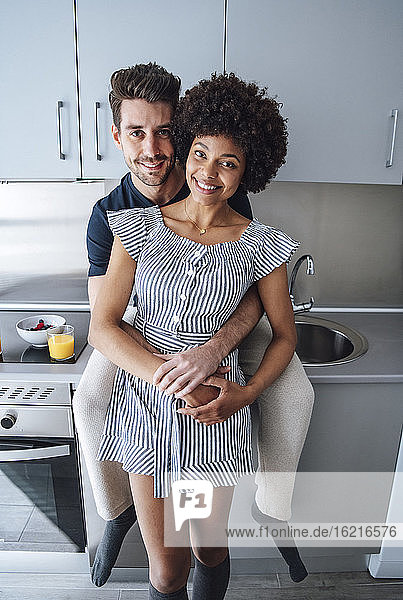 Romantisches multiethnisches Paar umarmt sich in der Küche eines Penthouses