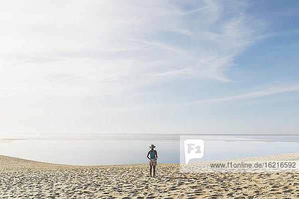 Frau schaut auf den Atlantik  während sie an einem sonnigen Tag am Strand steht  Düne von Pilat  Nouvelle-Aquitaine  Frankreich