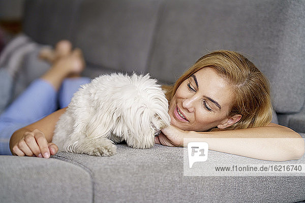 Frau entspannt sich mit Hund auf Sofa zu Hause
