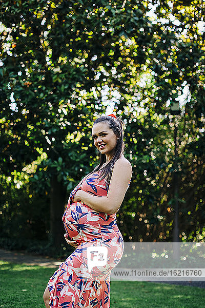 Lächelnde schwangere Frau in einem öffentlichen Park