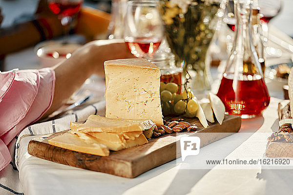 Cheese platter and wine on table with people in background
