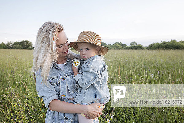 Mother holding her daughter in field