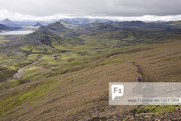Island  Zwei Männer beim Mountainbiking in hügeliger Landschaft