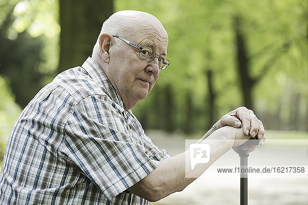 Deutschland  Nordrhein-Westfalen  Köln  Porträt eines älteren Mannes auf einer Bank sitzend mit Spazierstock im Park