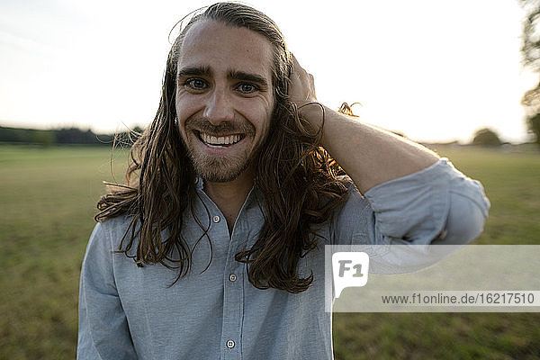 Porträt eines glücklichen jungen Mannes auf einer Wiese auf dem Lande