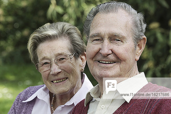 Germany  Cologne  Portrait of senior couple sitting in park  smiling