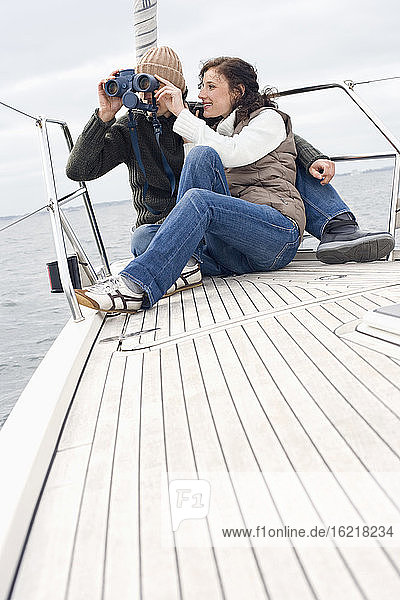 Germany  Baltic Sea  Lübecker Bucht  Young couple on boat  man looking through binoculars