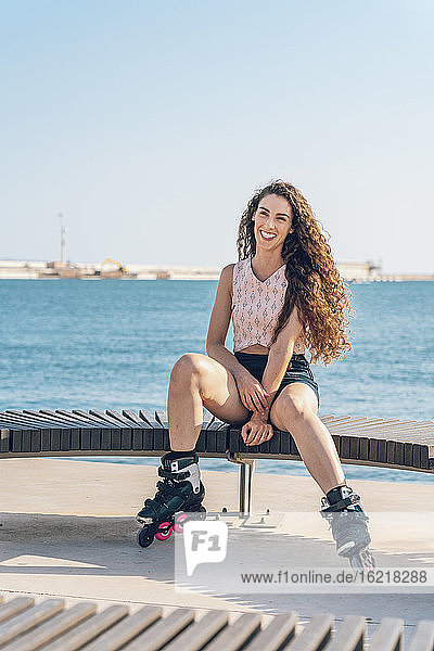 Junge Frau mit Inline-Skates auf einer Bank sitzend