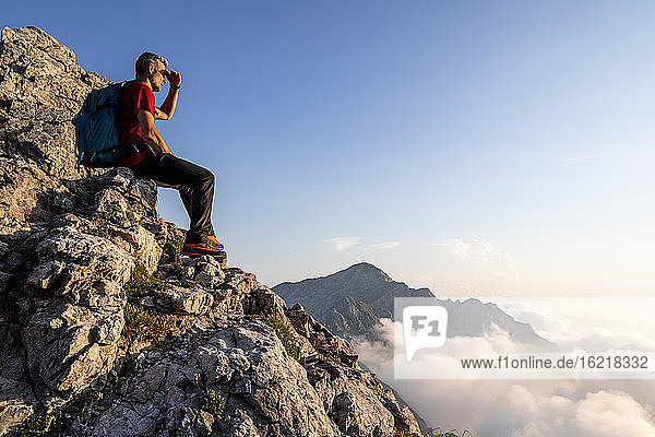 Hiker looking at view while sitting on mountain at Bergamasque Alps  Italy