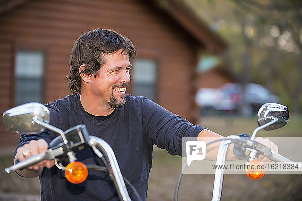 USA  Texas  Älterer Mann auf Motorrad sitzend  lächelnd