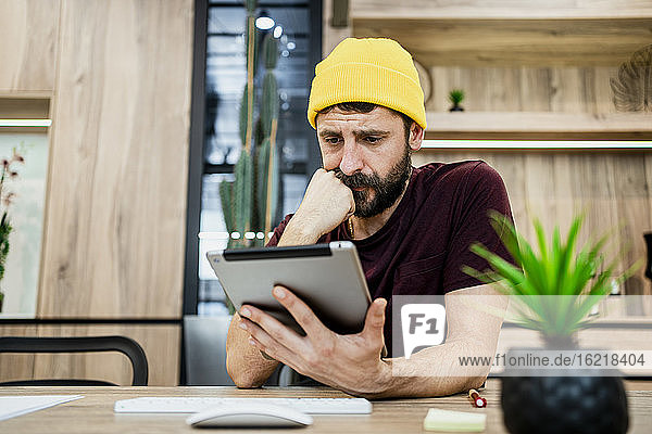 Geschäftsmann mit digitalem Tablet am Schreibtisch in einem modernen Büro