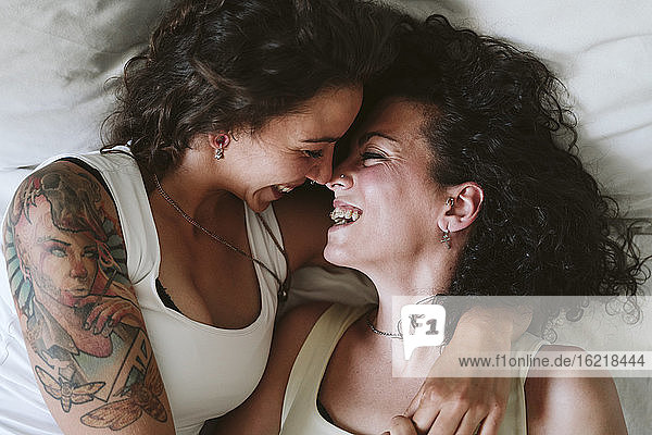 Nahaufnahme eines glücklichen lesbischen Paares  das sich küsst  während es zu Hause auf dem Bett liegt