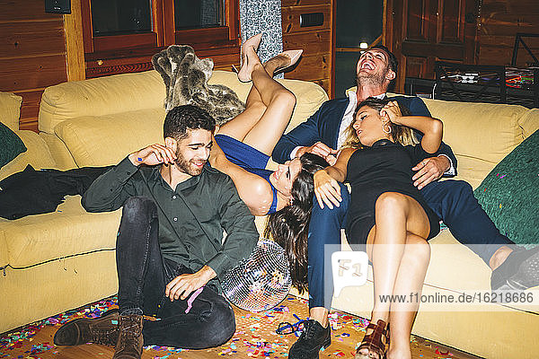 Cheerful drunk friends resting on sofa in party
