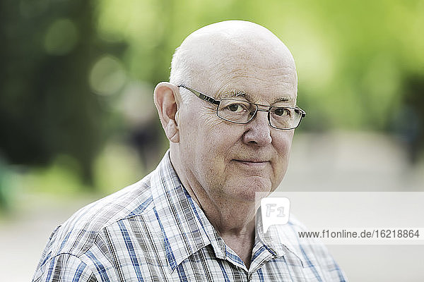 Deutschland  Nordrhein-Westfalen  Köln  Porträt eines älteren Mannes mit Brille im Park  lächelnd