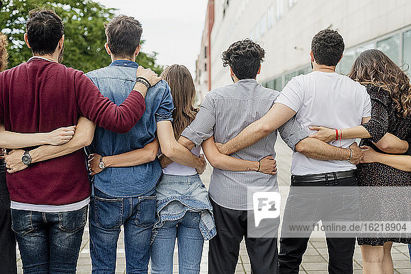 Männliche und weibliche Freunde  die sich umarmen und auf einem Fußweg in der Stadt stehen