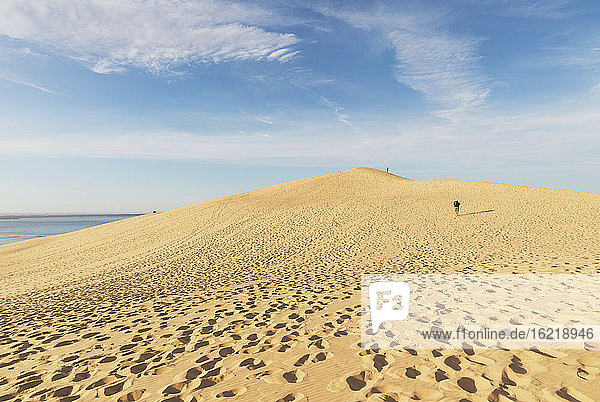 Blick auf einen Mann  der auf einer Sanddüne gegen den Himmel läuft  Düne von Pilat  Nouvelle-Aquitaine  Frankreich
