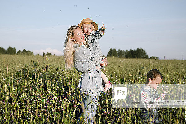 Smiling mother with two children walking on field
