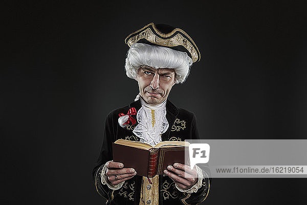 Porträt eines reifen Mannes in Tracht  der ein Buch liest