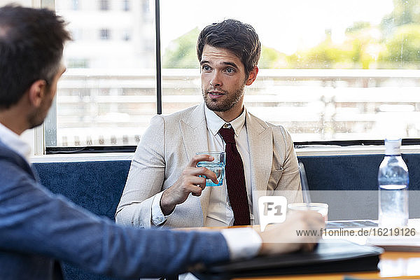 Confident businessman discussing with coworker during meeting in restaurant