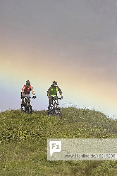 Island  Zwei Männer beim Mountainbiking in hügeliger Landschaft