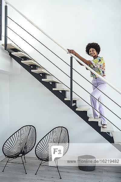 Glückliche Frau steht auf einer schwebenden Treppe in einem modernen Penthouse