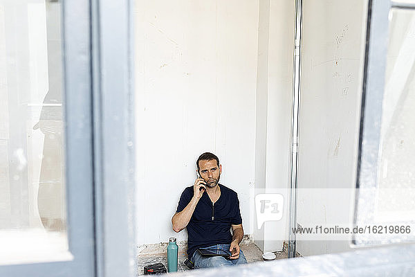 Arbeiter am Telefon bei einer Pause in einem im Bau befindlichen Haus