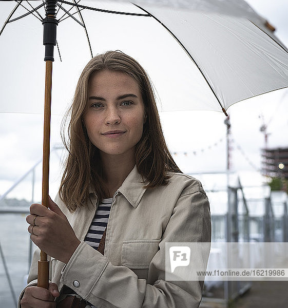 Close-up of young woman with umbrella standing in city