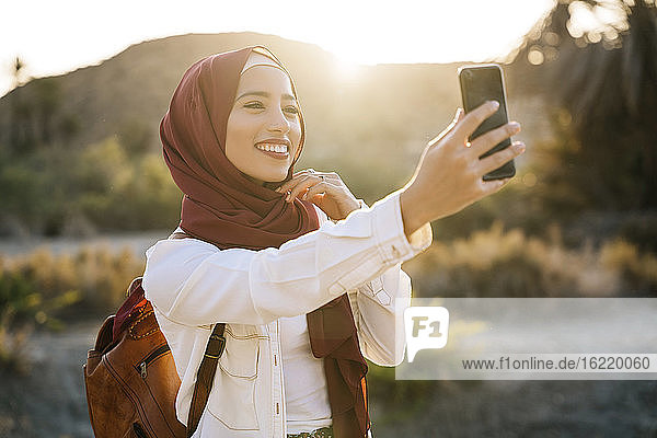 Lächelnde junge Touristin  die einen Hijab trägt und ein Selfie macht
