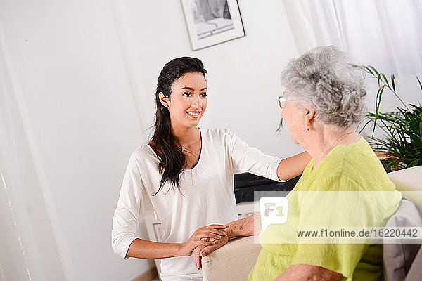 cheerful young girl taking care of elderly senior woman at home