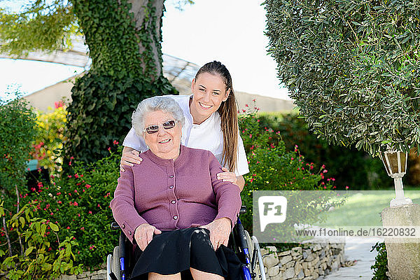 Ältere ältere Frau im Rollstuhl mit einer Krankenschwester im Freien in Pflegeheim Krankenhaus Garten.