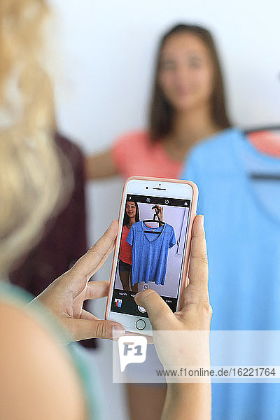 Junger Teenager zu Hause mit einem Smartphone  der die Vinted-App nutzt  um seine Kleidung zu verkaufen